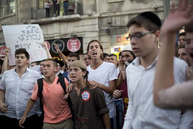 At a right-wing protest in Jerusalem a sign reads “May God avenge their blood” and a youth wears a sticker stating “Kahane was right,” referring to the Brooklyn-born violent settler movement leader, 1 July.