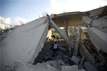 Palestinian men inspect a destroyed building following an Israeli military strike on Beit Lahya, northern Gaza Strip on July 15, 2014
