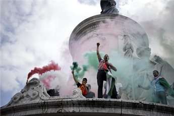 Pro-Palestinian demonstrators spray fumes with the colours of the Palestinian flag, on the Republique square in Paris, during a banned demonstration against Israel