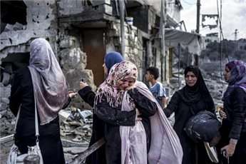Palestinian women struggle to take in the destruction in the Beit Hanoun area of Gaza during an humanitarian truce on July 26, 2014