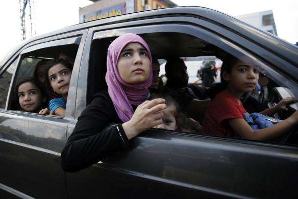 Palestinians fleeing in a vehicle from Israeli shelling in Bet Lahiya look up as a fighter jet flies overhead in northern Gaza Strip July 21 2014.