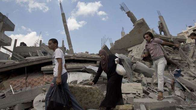 Palestinians walk across the rubble of buildings destroyed in Israeli attacks in southern Gaza on August 4, 2014.