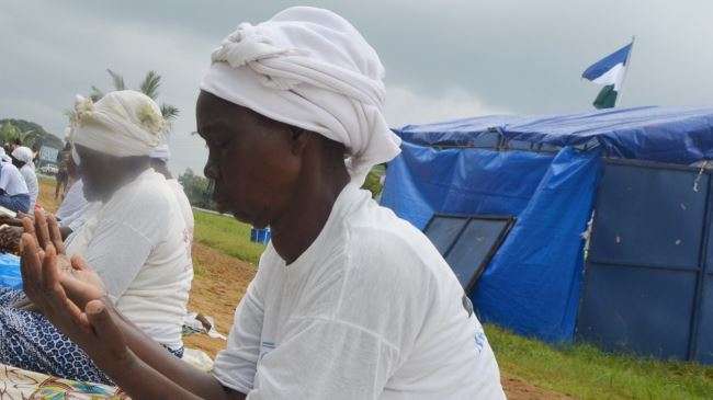 Members of Women in Peace Building Network (WIPNET) pray on August 6, 2014 on a field not far from Liberia