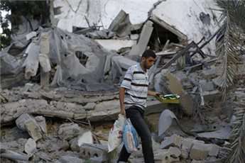 A Palestinian man collects belongings as he inspects a house after it was destroyed by an Israeli air strike early on July 16, 2014, in Gaza City.