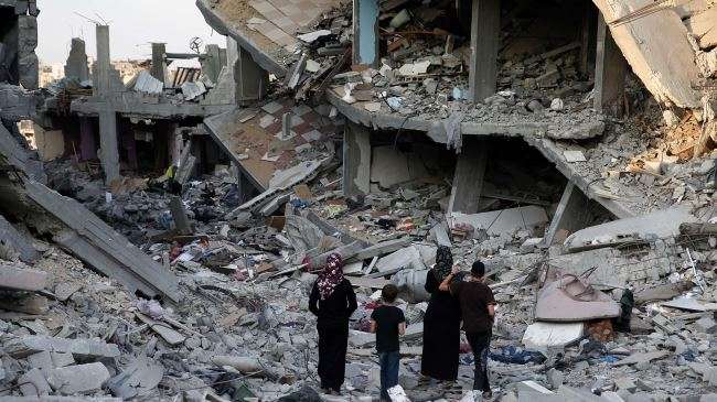 Palestinians walk in the rubble of destroyed houses in Gaza City
