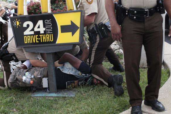 Police officers detain a demonstrator for protesting Michael Brown murder in Ferguson, Missouri August 18, 2014.