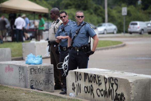 Police officers keep an eye on demonstrators protesting Michael Brown murderin Ferguson, Missouri August 18, 2014.