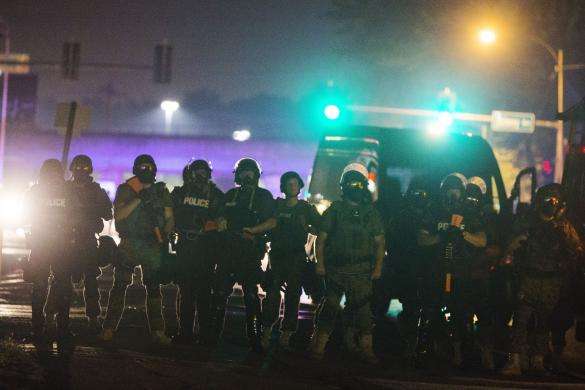 Police officers line up across the street as they maintain their distance from protesters during on-going demonstrations to protest against the shooting of Michael Brown, in Ferguson, Missouri, August 16, 2014.