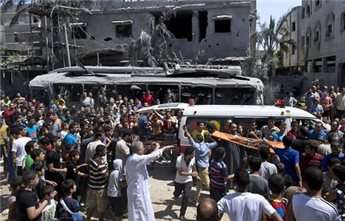 Palestinians crowd around an ambulance in Gaza City as a deceased victim of an Israeli strike is removed from the rubble of a house on August 20, 2014.