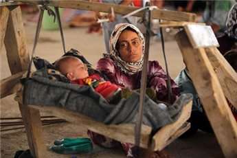 An Iraqi Yazidi woman, who fled her home when Islamic State militants attacked the town of Sinjar, looks at her baby as they rest inside a building under construction outside the Kurdish city of Dohuk, on Aug. 16, 2014