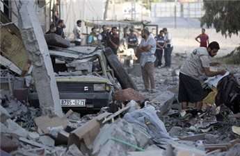 Palestinians collect belongings next to the house of senior Hamas official Mahmud al-Zahar after it was destroyed by an Israeli air strike, on July 16, 2014, in Gaza City