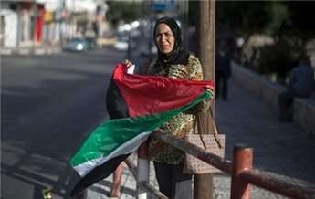 A woman waves the national flag as she celebrates the agreement to form a unity government in Gaza on April 23, 2014.