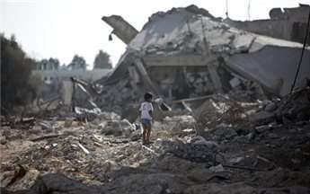 A Palestinian boy walks over debris as civilians who were displaced from their houses due to fighting between Israel