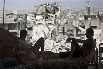 Palestinians sit inside their destroyed house in the Tuffah neighborhood in eastern Gaza City on August 31, 2014