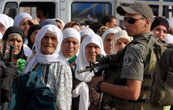 An Israeli border policeman stands near Palestinian women at the Qalandia checkpoint between Ramallah and Jerusalem in 2008