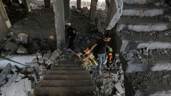Gazans inspect the rubble of their building destroyed by an Israeli airstrike on July 13, 2014.