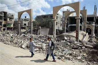 Palestinian girls walk past the rubble of a building that was destroyed during the Israeli army summer