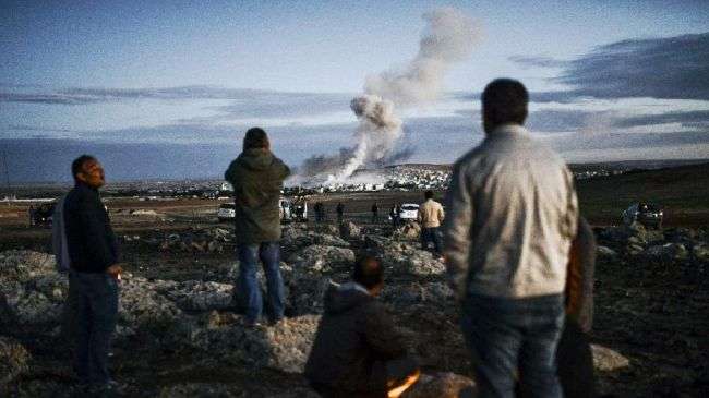 People observe smoke rising from the Syrian town of Kobani on October 20, 2014.