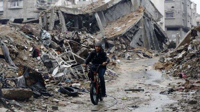 A Palestinian rides his bike past houses that were destroyed during the 50-day Israeli war on the Gaza Strip in Gaza City, November 16, 2014.