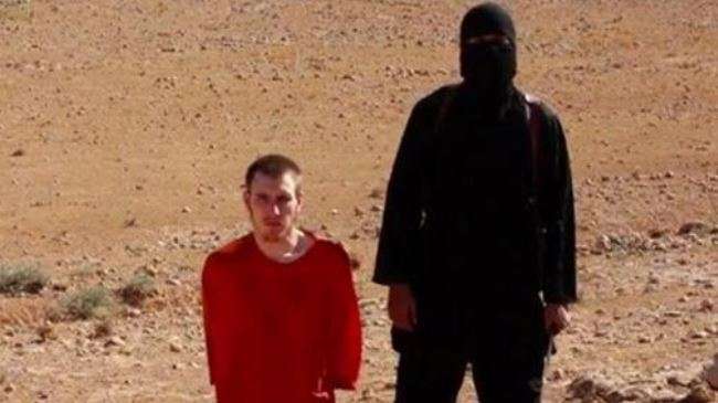 A masked man stands next to a kneeling man identified as US citizen Peter Kassig (L), in this still image taken from video released by ISIL militants.