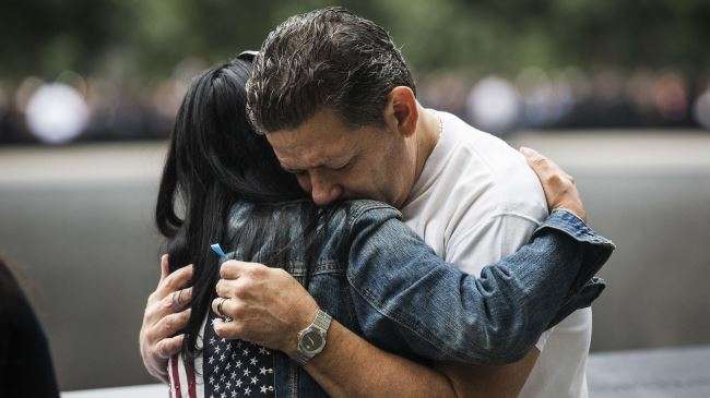 Eileen Esquilin hugs her husband, Joe Irizarry, while mourning the loss of her brother, Ruben Esquilin Jr, during the memorial observances held at the site of the World Trade Center in New York, September 11, 2014.