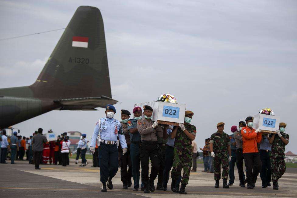 Indonesian military personnel carry caskets containing the remains of passengers onboard AirAsia flight QZ8501, recovered off the coast of Borneo, at a military base in Surabaya, January 3, 2015.