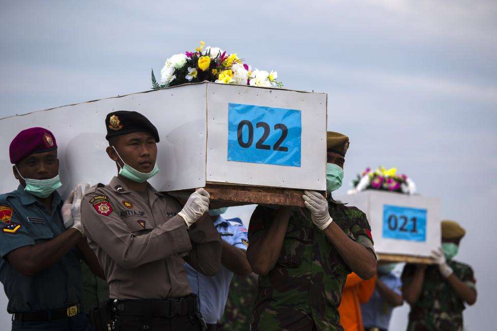 Indonesian military personnel carry caskets containing the remains of passengers onboard AirAsia flight QZ8501, recovered off the coast of Borneo, at a military base in Surabaya, January 3, 2015.