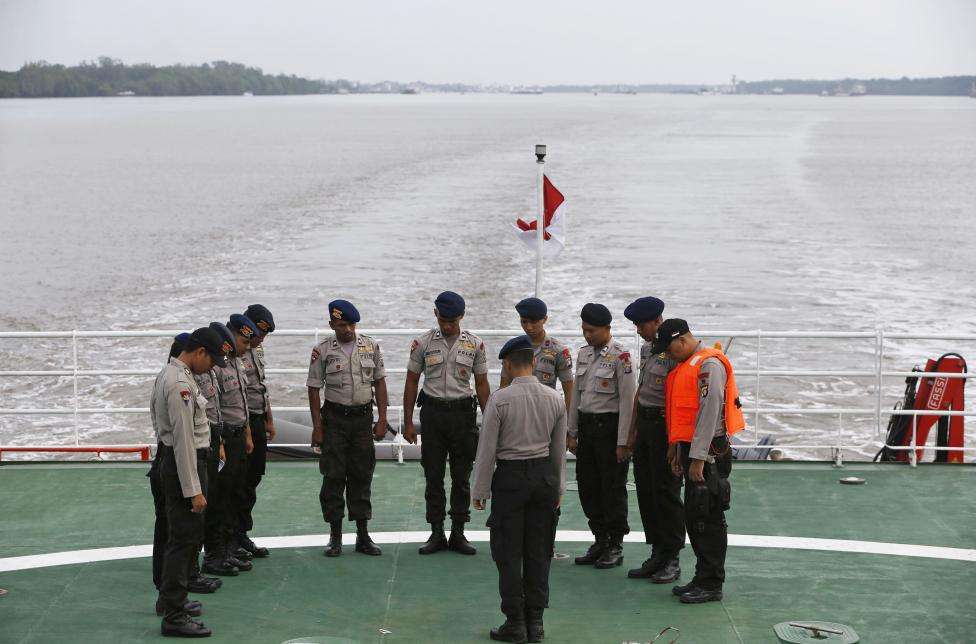 Indonesian policemen involved in the search operation for passengers onboard AirAsia Flight QZ8501 pray onboard the deck of the Search and Rescue ship KN Purworejo in the Java Sea, January 3, 2015.