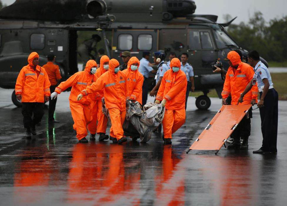 Search and Rescue crews carry part of AirAsia QZ8501 transported to shore by a Singapore Navy helicopter at the airbase in Pangkalan Bun, Central Kalimantan, January 4, 2015.