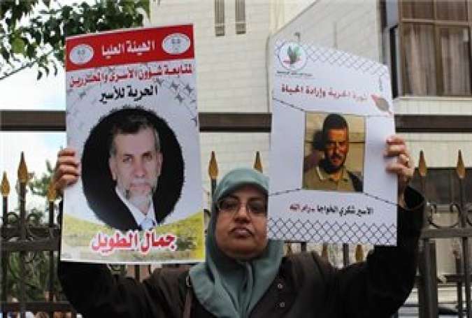 A Palestinian women holds up photos of prisoners at a support rally in al-Bireh for over 100 hunger striking administrative detainees on May 13, 2014