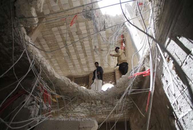 Yemeni men look through a hole in a building damaged by a recent Saudi airstrike in the capital, Sana’a, on April 25, 2015.