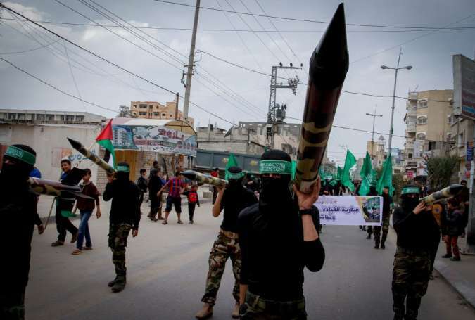 Masked Hamas members carry a model of a rocket during a rally in the central Gaza