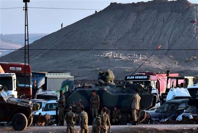 ISIL militants (Rear) stand atop a hill in the Syrian town of Ain al-Arab, known as Kobani by the Kurds, as seen from the Turkish-Syrian border, with Turkish troops in foreground.