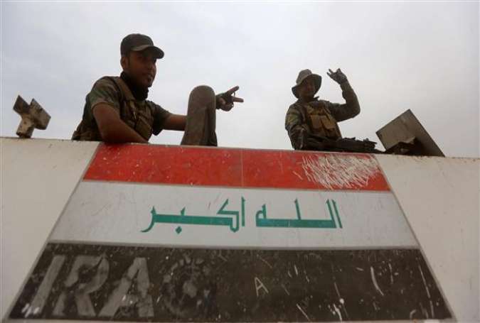 Iraqi Shia volunteer fighters from the Popular Mobilization units flash the V sign for victory atop their vehicle on the Tharthar frontline on the edge of Anbar province on June 1, 2015.