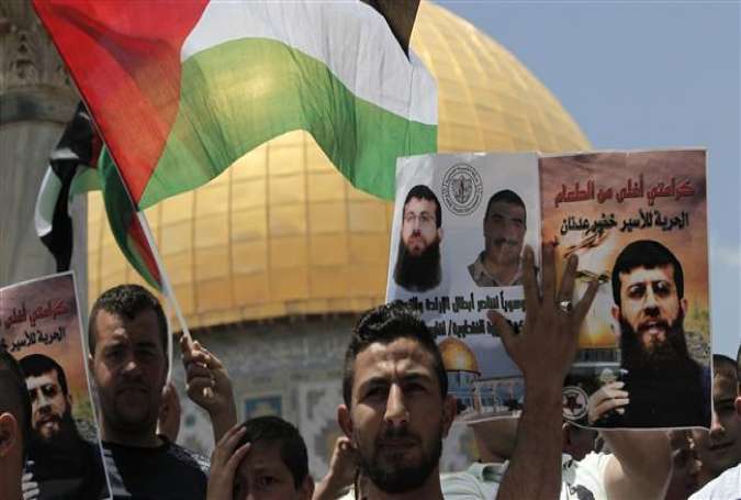 Protesters in al-Quds chant slogans during a demonstration in support of Palestinian prisoner Khader Adnan (portrait), who is in an Israeli jail without trial, June 5, 2015.