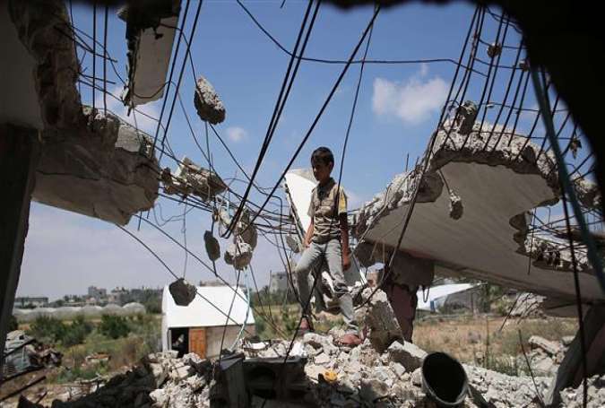 A Palestinian boy plays in the rubble of houses destroyed during the 50-day Israeli assault on Gaza in the summer of 2014, in the village of Khuza’a, east of Khan Yunis, in the southern Gaza Strip on July 7, 2015.