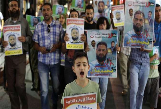 Palestinian protesters take part in a rally in solidarity with Mohammed Allan (shown in portraits) in the occupied West Bank city of Ramallah on August 19, 2015.