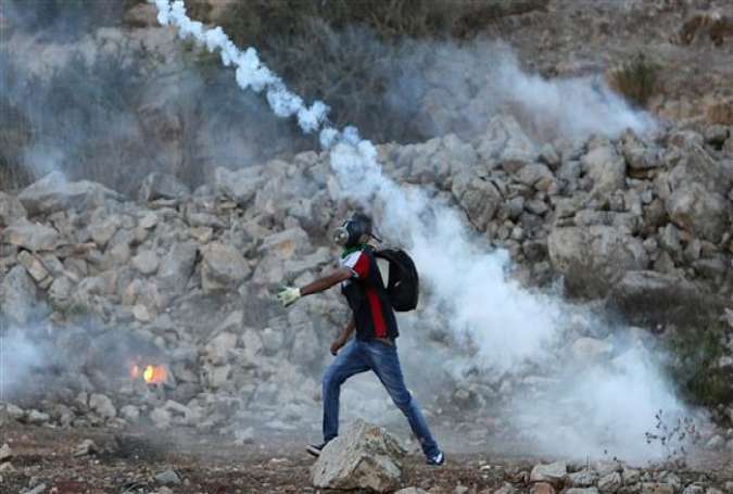 A Palestinian protester throws back a tear gas canister that was fired by Israeli troops (unseen) during clashes outside the Ofer military prison near the occupied West Bank city of Ramallah, after a march by Palestinians against violations of al-Aqsa Mosque compound in al-Quds (Jerusalem), September 17, 2015.
