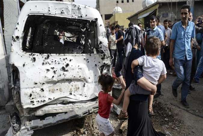 People walk past a van damaged in clashes between Turkish forces and the militants of the Kurdistan Workers’ Party (PKK) in the city of Cizre, in southeastern Turkey, September 12, 2015.