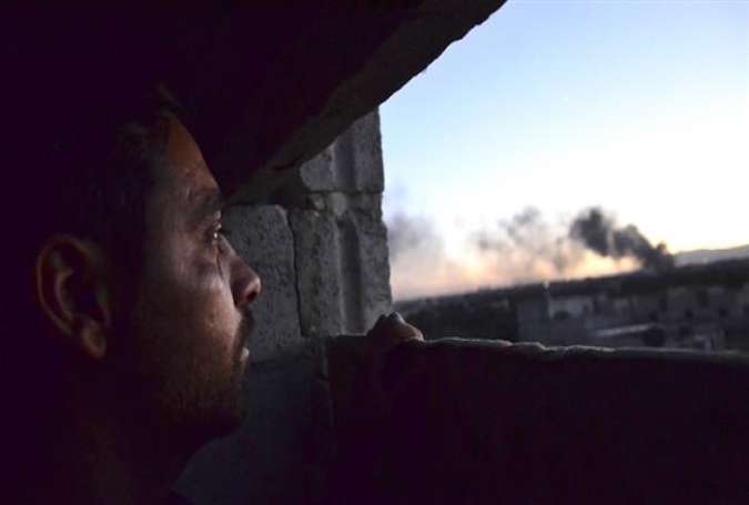 A man looks at smoke rising into the sky from what reportedly was Free Syrian Army fighters destroying a tank that belonged to the Syrian army in the al-Qaboun area, eastern Ghouta, September 15, 2015.