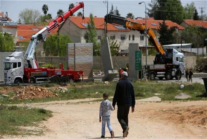 Two Palestinians walk near the Israeli settlement of Beit El, north of Ramallah, in the occupied West Bank, April 7, 2015