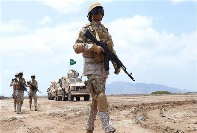 A member of the Saudi forces stands in front of military vehicles in Yemen