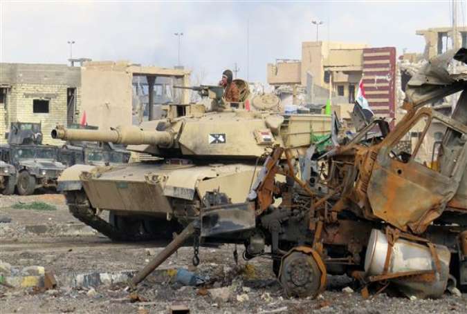 Iraqi counter-terrorism forces drive a tank past rubble south of Anbar’s provincial capital city of Ramadi on December 25, 2015.
