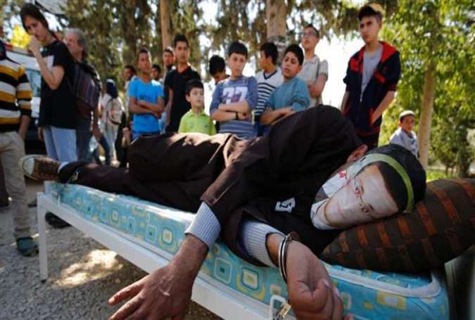 A Palestinian man lying on a bed wears a face covering depicting hunger striking Palestinian journalist Mohammed al-Qiq, on February 19, 2016, during a demonstration in solidarity with him in the West Bank village of Bilin, near Ramallah.