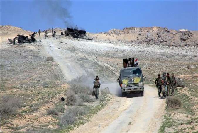 Syrian government forces advance on a road through the town of Khanasir after they recaptured it from Daesh terrorists, on February 29, 2016.