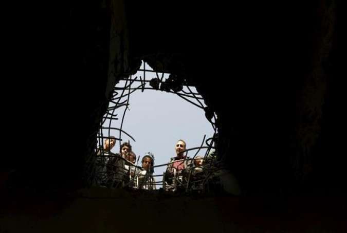 People look through a hole caused by a Saudi airstrike on a bridge in Yemen