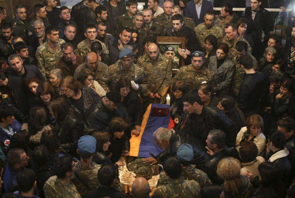 People surround a coffin with the body of an Armenian serviceman, who was killed in clashes over the breakaway Nagorno-Karabakh region according to Armenian officials, during a memorial service at a church in Yerevan, Armenia, April 4, 2016.