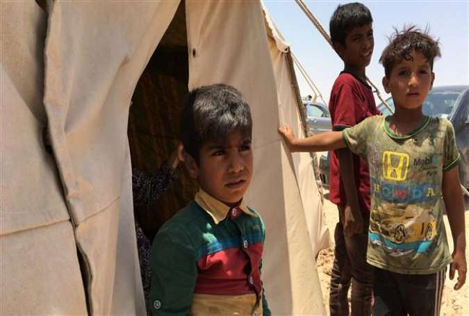 Displaced Iraqi boys stand in front of a tent at a newly-opened camp in the government-held town of Amriyat al-Fallujah, 50 kilometers (30 miles) southwest of Baghdad, which was set up to shelter people fleeing violence around the central city of Fallujah, May 29, 2016.