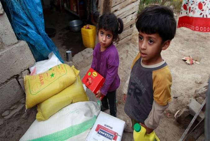 Yemeni children stand next to food rations that a local charity is distributing to families affected by the Saudi war on their country, in the capital Sana