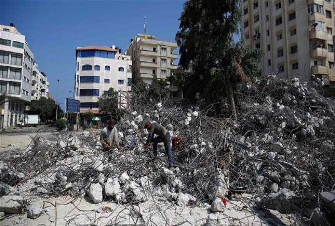 Palestinian workers remove debris from buildings destroyed during the 2014 Israeli offensive in Gaza City, August 10, 2016.